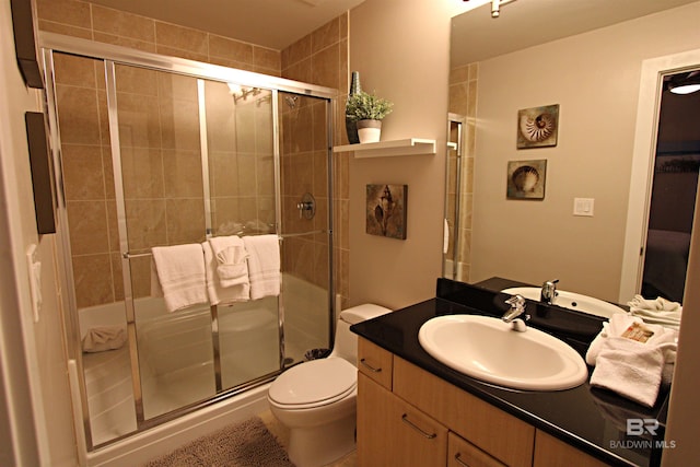 bathroom featuring vanity, toilet, and a shower with shower door