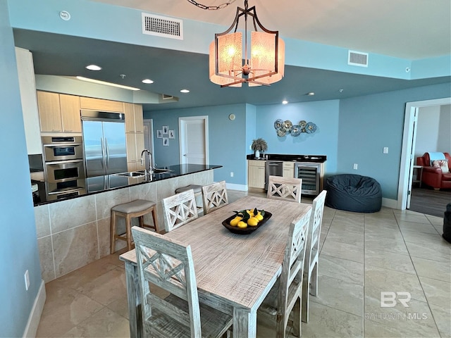 tiled dining space with sink, wine cooler, and a chandelier