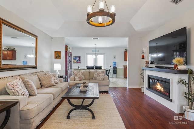1500 Thames Dr, Foley, AL 36535 - living room featuring dark wood finished floors, a glass covered fireplace, a raised ceiling, baseboards, and a notable chandelier