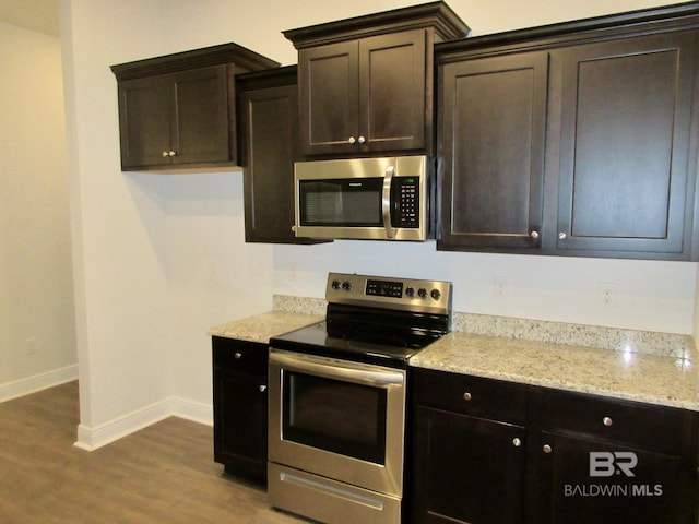 kitchen with light stone countertops, dark brown cabinets, dark hardwood / wood-style floors, and stainless steel appliances