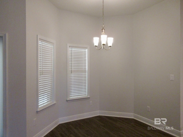 spare room featuring dark hardwood / wood-style flooring and an inviting chandelier