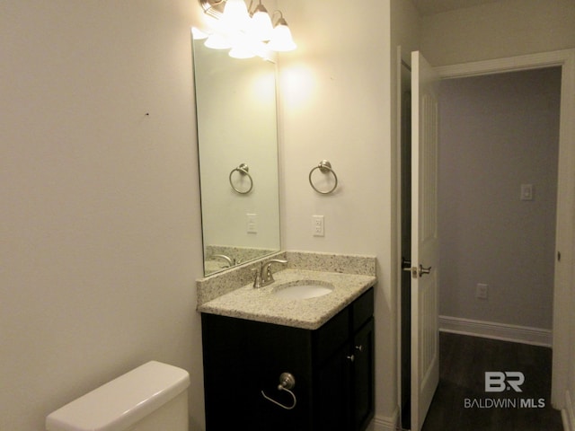 bathroom featuring toilet, vanity, and a notable chandelier