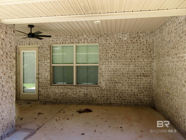 unfurnished room with ceiling fan and brick wall