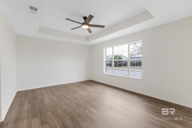 unfurnished room featuring dark hardwood / wood-style flooring, a raised ceiling, and ceiling fan