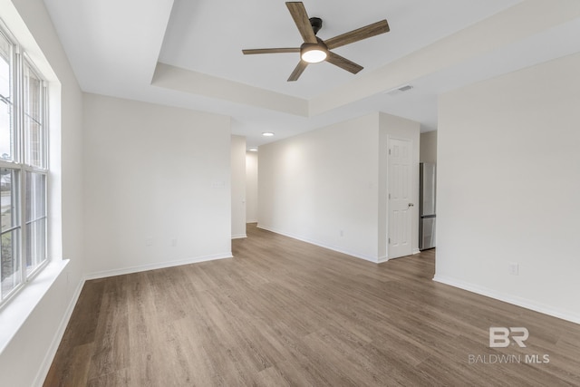 unfurnished room featuring hardwood / wood-style flooring, a raised ceiling, and ceiling fan