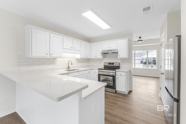 kitchen with white fridge, kitchen peninsula, white cabinets, and stainless steel range with electric stovetop