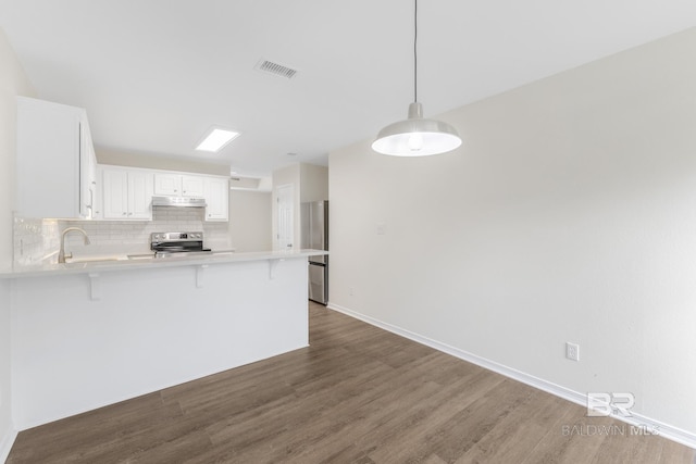 kitchen featuring pendant lighting, white cabinetry, stainless steel appliances, a kitchen bar, and kitchen peninsula