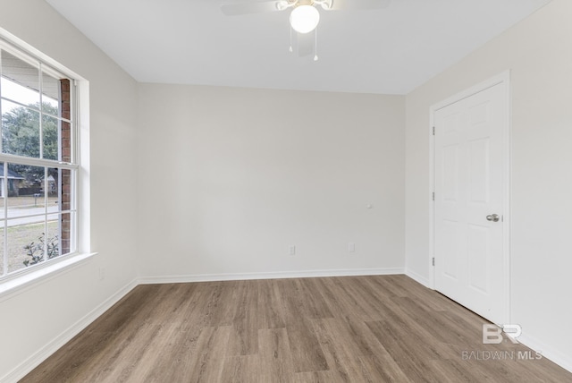 empty room with wood-type flooring, a healthy amount of sunlight, and ceiling fan