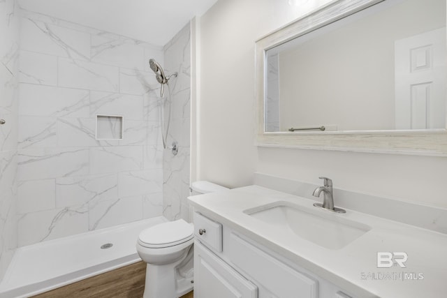 bathroom featuring vanity, toilet, hardwood / wood-style floors, and a tile shower