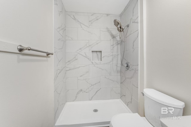 bathroom featuring a tile shower and toilet