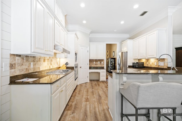 kitchen featuring white cabinets, stainless steel appliances, kitchen peninsula, and dark stone countertops