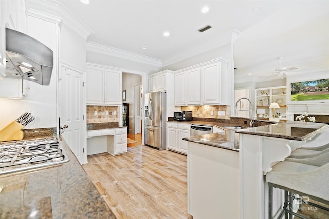 kitchen with white cabinetry, kitchen peninsula, dark stone countertops, and appliances with stainless steel finishes