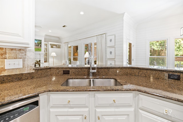 kitchen featuring sink, white cabinetry, stainless steel dishwasher, and dark stone countertops