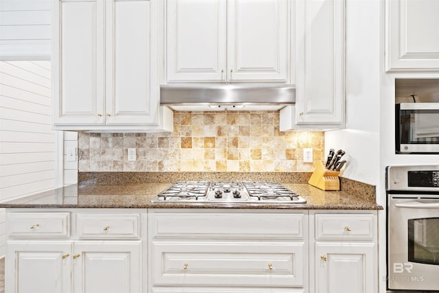 kitchen featuring appliances with stainless steel finishes, white cabinetry, and dark stone countertops