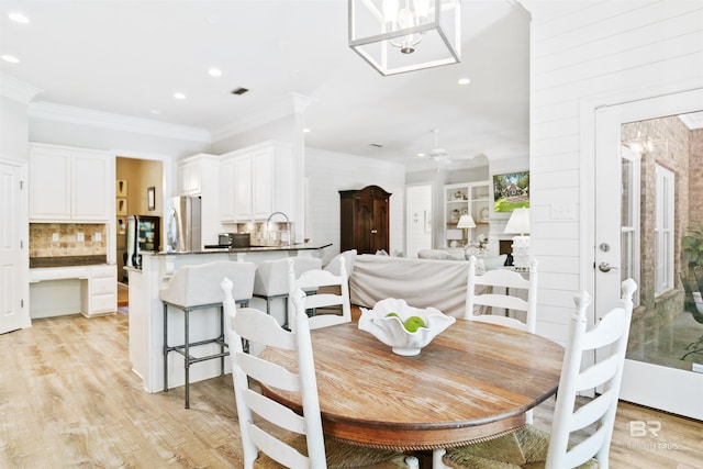 dining room with light hardwood / wood-style flooring, ceiling fan, ornamental molding, and sink