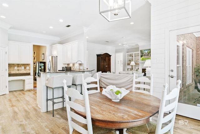 dining room with sink, crown molding, light hardwood / wood-style flooring, and ceiling fan