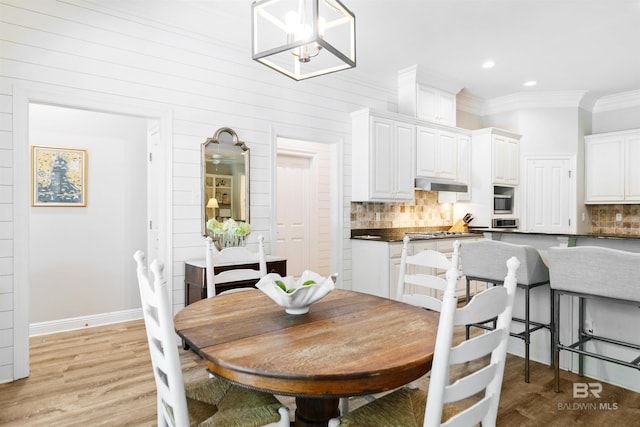 dining room with a chandelier, light hardwood / wood-style flooring, and crown molding