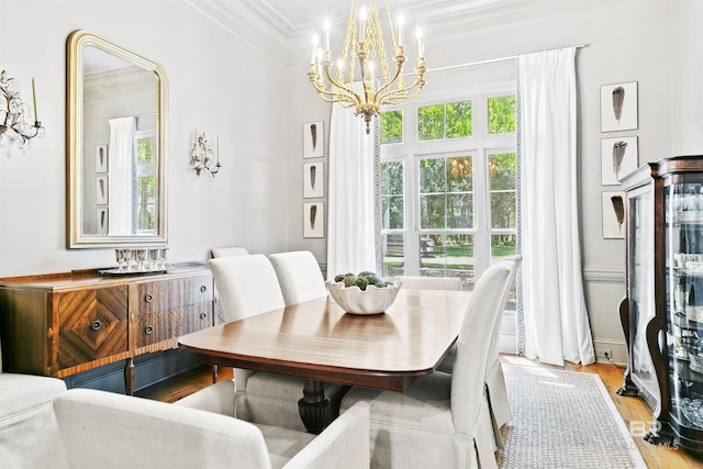 dining space with a notable chandelier, light hardwood / wood-style floors, and crown molding