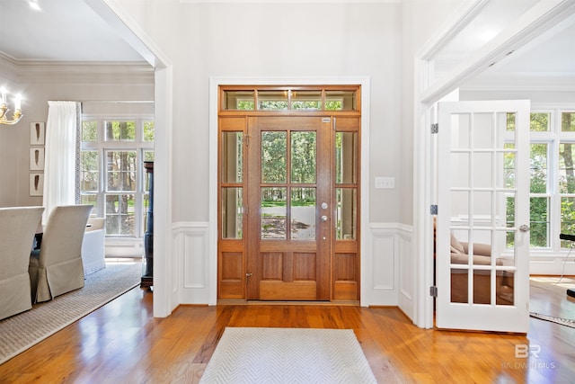 entrance foyer featuring french doors, light wood-type flooring, and ornamental molding