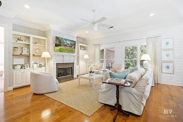 living room with wood walls, ceiling fan, light hardwood / wood-style floors, and ornamental molding