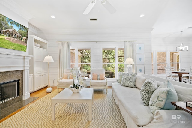 living room featuring a premium fireplace, ceiling fan, and light wood-type flooring