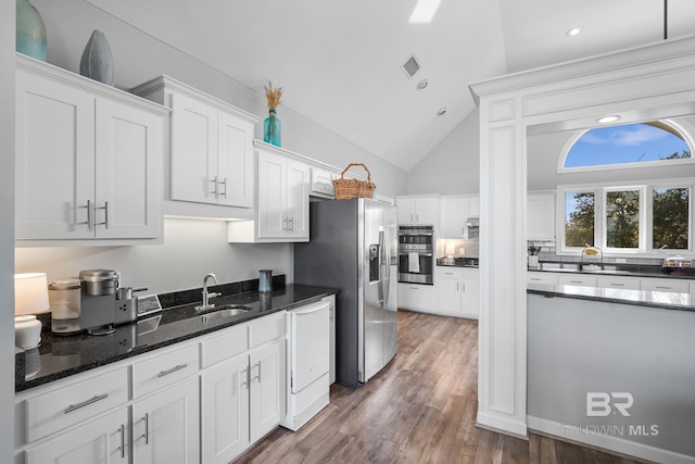 kitchen featuring dark hardwood / wood-style flooring, sink, white cabinetry, appliances with stainless steel finishes, and dark stone countertops