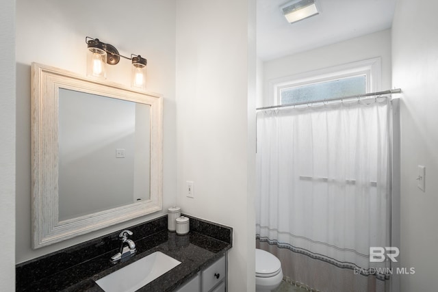 bathroom with toilet, vanity, and curtained shower