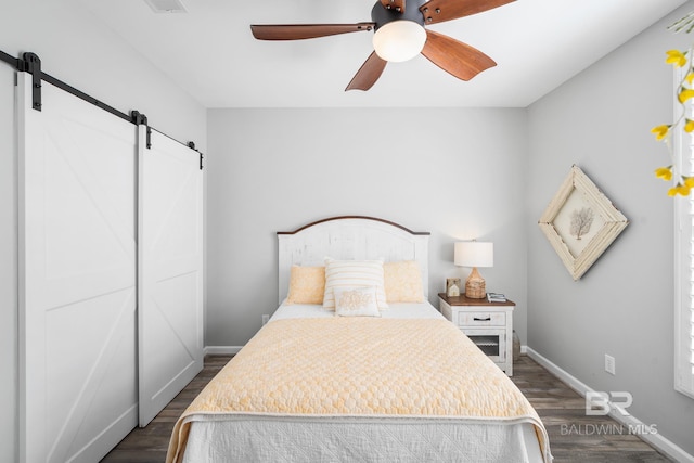 bedroom featuring a barn door, dark hardwood / wood-style floors, and ceiling fan