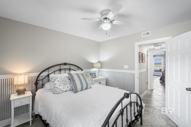 bedroom featuring wood walls, ceiling fan, and tile patterned floors