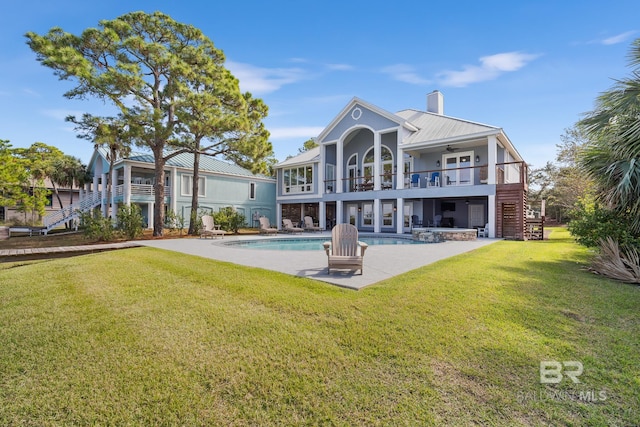 rear view of property featuring a patio area, a yard, and a balcony