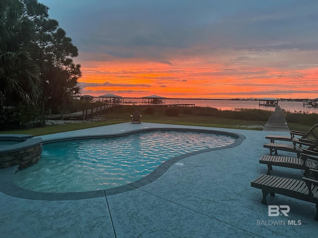 pool at dusk featuring a water view