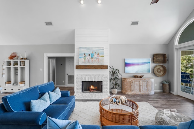 living room with hardwood / wood-style floors, vaulted ceiling, and a brick fireplace