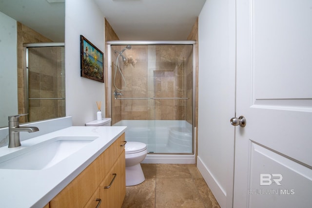 full bathroom featuring a shower stall, vanity, stone finish flooring, and toilet