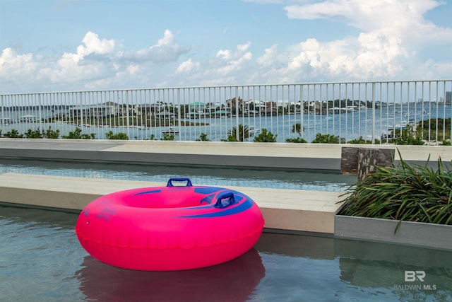 view of pool featuring a water view and fence