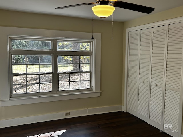 unfurnished bedroom featuring ceiling fan, dark wood-type flooring, and a closet