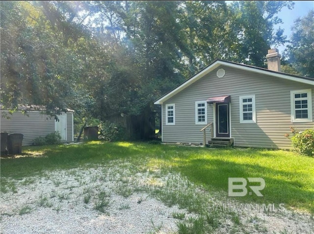 view of front of house with a storage unit and a front lawn