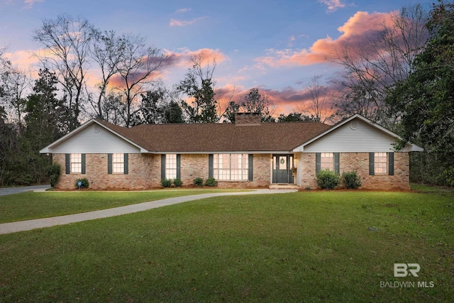 ranch-style home with brick siding, a lawn, and a chimney