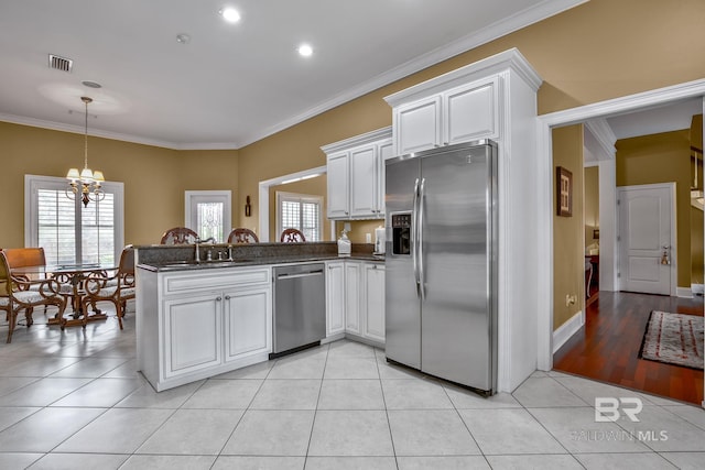 kitchen featuring kitchen peninsula, light tile floors, appliances with stainless steel finishes, and white cabinetry