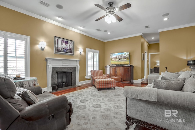 living room featuring a healthy amount of sunlight, ceiling fan, wood-type flooring, and crown molding