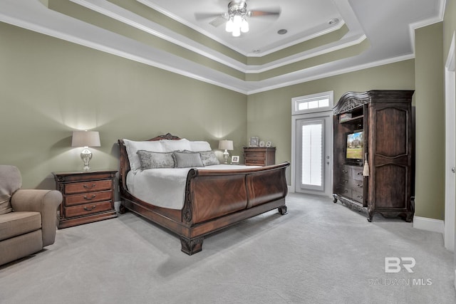 carpeted bedroom with crown molding, a tray ceiling, and ceiling fan