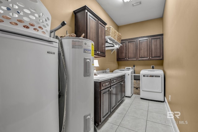 laundry room featuring light tile floors, hookup for a washing machine, washing machine and clothes dryer, water heater, and cabinets