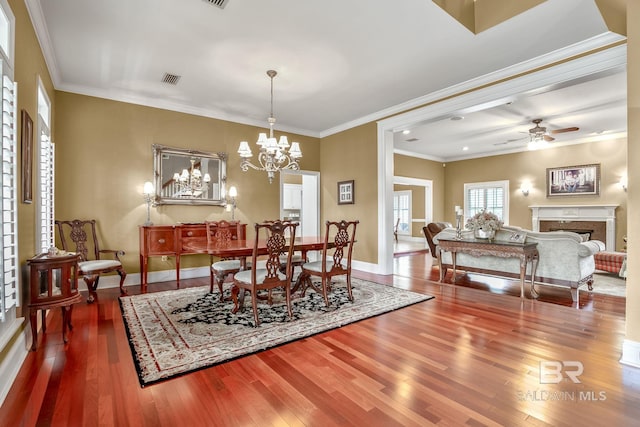 dining space featuring crown molding, ceiling fan with notable chandelier, and dark hardwood / wood-style flooring