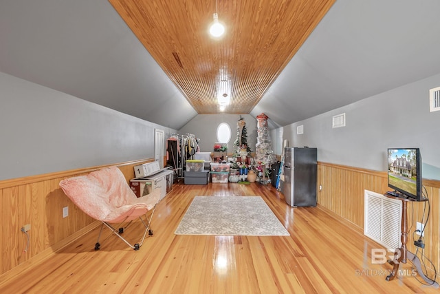 interior space featuring stainless steel fridge, light hardwood / wood-style flooring, and vaulted ceiling