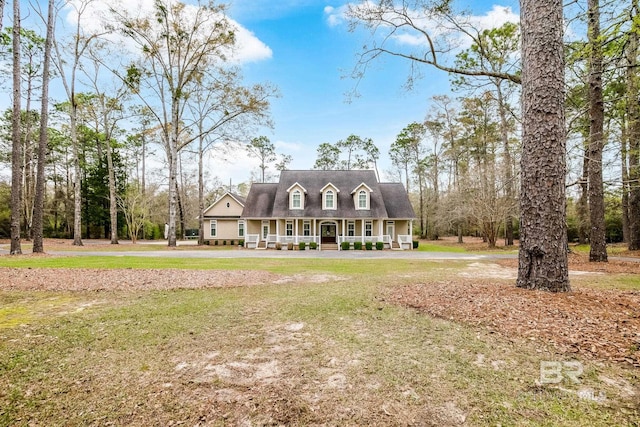 cape cod home with covered porch and a front yard