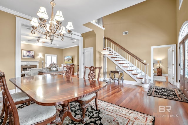 dining room featuring ceiling fan with notable chandelier, a high ceiling, hardwood / wood-style flooring, and crown molding