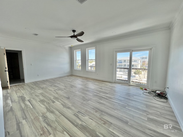 empty room with crown molding, baseboards, visible vents, and light wood-type flooring