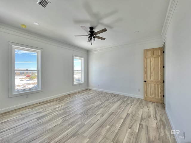 empty room featuring ceiling fan, visible vents, baseboards, ornamental molding, and light wood-style flooring