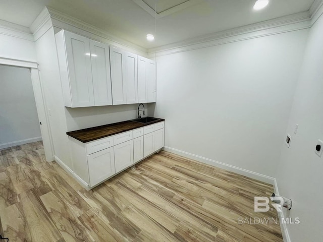 laundry area with crown molding, baseboards, electric dryer hookup, a sink, and light wood finished floors