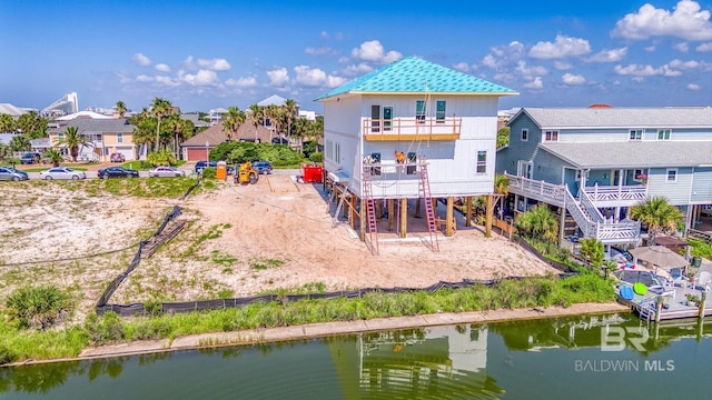 back of house with a residential view, stairs, a water view, a balcony, and a carport