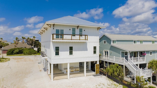 back of house with a patio, cooling unit, a balcony, and dirt driveway